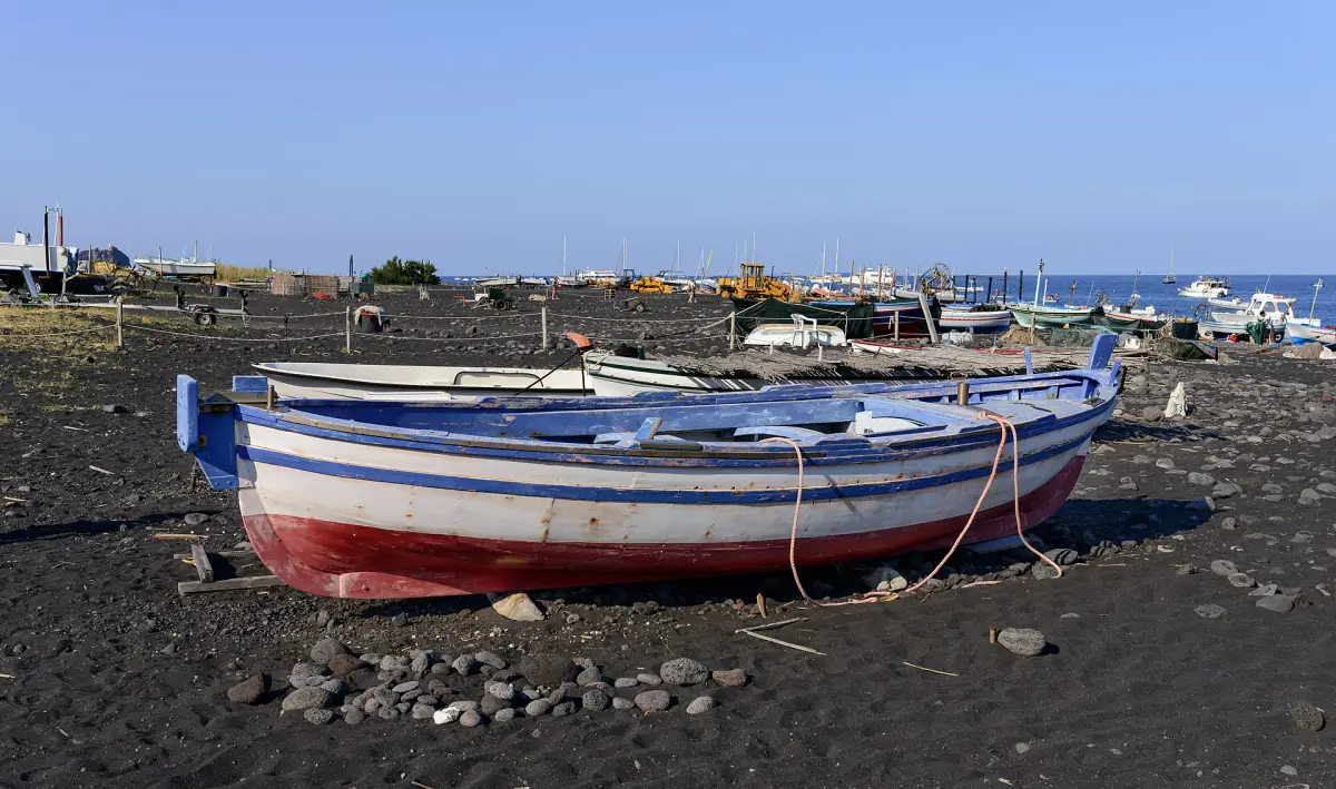 Ein Fischerboot auf dem schwarzen Sand